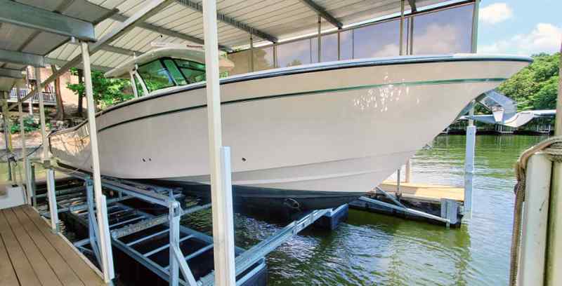 Nice, large boat sits safely on a floating boat lift for sale in Lake Ozark, MO.