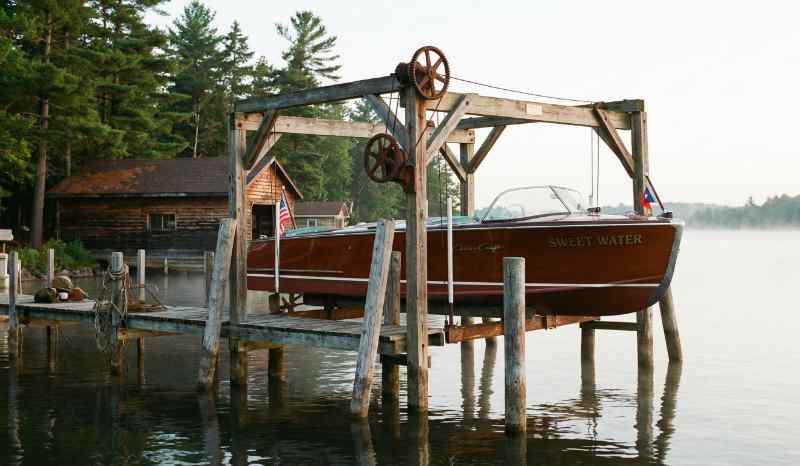 A traditional boat lift set on pilings in a lake.