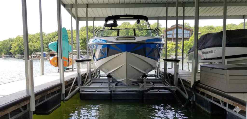 A wake boat centered on a floating boat lift designed for shallow water docks at Lake of the Ozarks.
